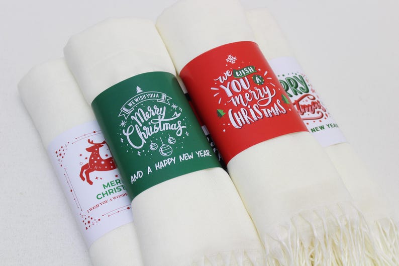 Pode incluir: Tr&ecirc;s sacos de presente de tecido branco com etiquetas de presente de papel com tema natalino. As etiquetas s&atilde;o de cor verde, vermelha e branca com texto de caligrafia manuscrito. O texto nas etiquetas diz "We wish you a Merry Christmas and a Happy New Year", "We wish you a merry Christmas", e "Merry Christmas and a Happy New Year".