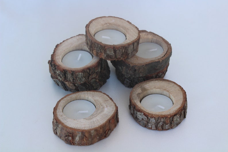 May include: Five wooden candle holders made from tree bark. Each holder has a round opening in the center to hold a tea light candle.