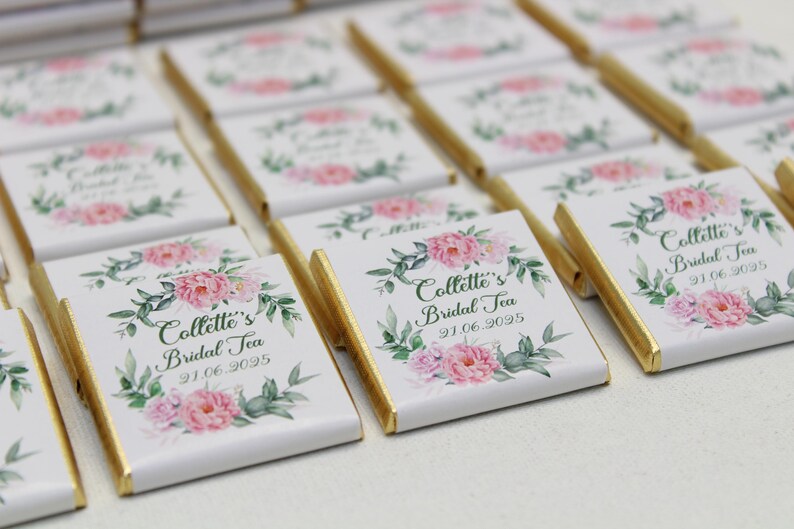Puede incluir: Una colecci&oacute;n de peque&ntilde;as barras de chocolate blanco con envoltorios de papel de aluminio dorado. Cada barra presenta un dise&ntilde;o floral con flores de acuarela rosa y verde y el texto "Collette's Bridal Tea 91.06.9095".