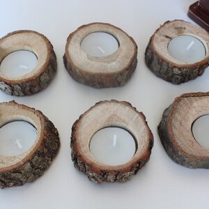 May include: Six wooden candle holders with a natural bark finish. Each holder has a circular opening in the center to hold a tea light candle.
