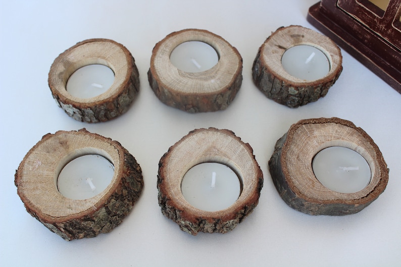 May include: Six wooden candle holders with a natural bark finish. Each holder has a circular opening in the center to hold a tea light candle.