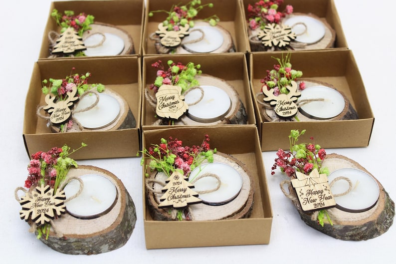 May include: Assortment of small, brown, wooden boxes with lids, each containing a small, white candle on a wooden slice. The wooden slices are decorated with dried flowers and small wooden ornaments with Christmas and New Year greetings.