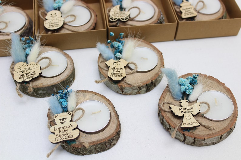 Op de afbeelding: Set van zes houten kaarshouders met theelichtjes, blauwe en witte gedroogde bloemen en gepersonaliseerde houten labels. De labels hebben babythema's en tekst zoals "Baby Shower", "Doop" en "Lorenzo's Baby Shower".
