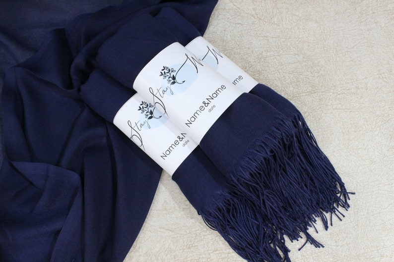 May include: Two navy blue pashmina scarves with fringe, wrapped and tied with a white label that says "Stay Strong" and "Name & Name date".