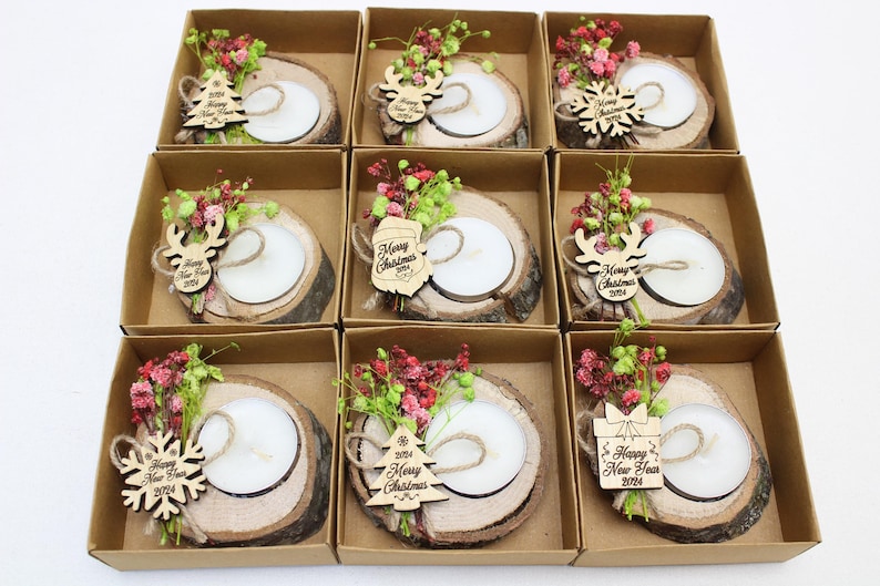 May include: Eight small wooden boxes with lids, each containing a small wooden candle holder with a white candle, a small wooden ornament, and dried flowers. The ornaments have the text "Merry Christmas 2024" or "Happy New Year 2024" on them.