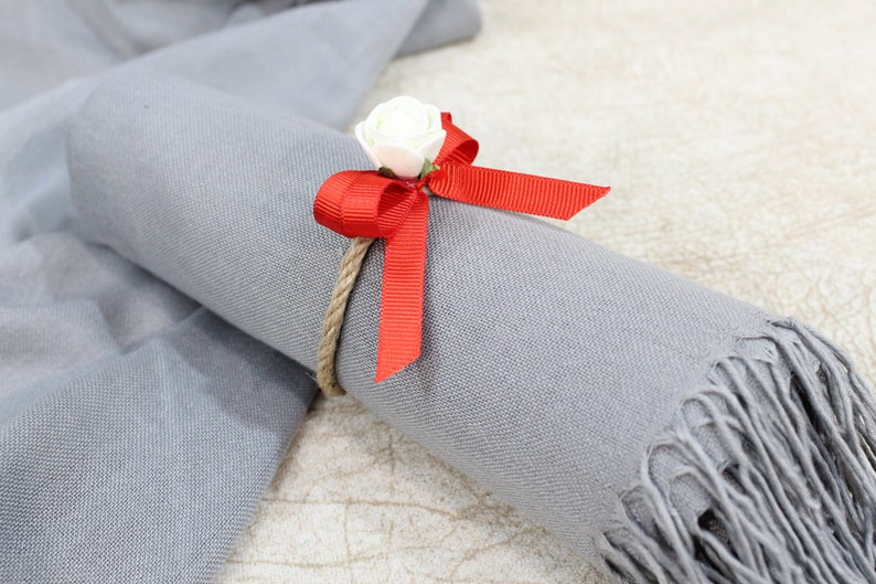 May include: A gray scarf with a red bow and a white flower tied around it.