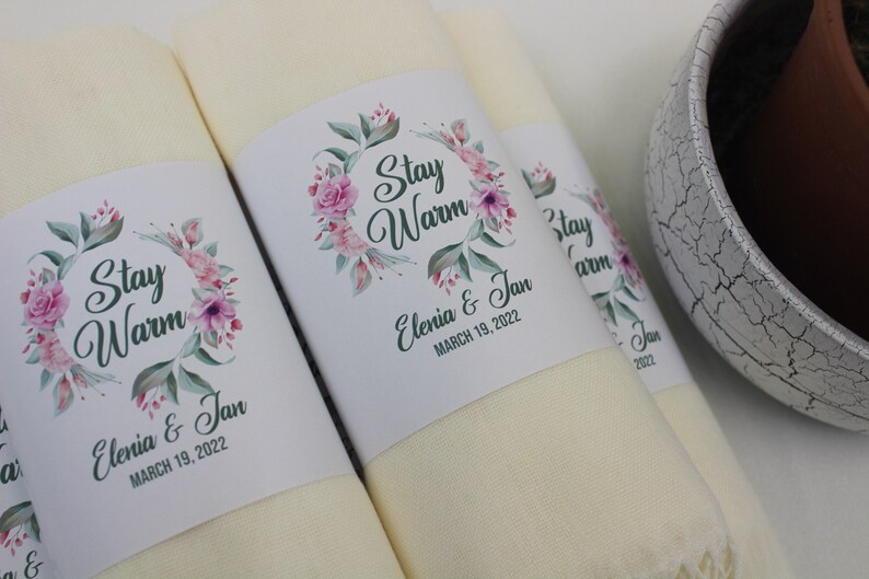May include: Two cream-colored towels with floral designs and the text "Stay Warm" and "Elenia & Jan March 19, 2022".