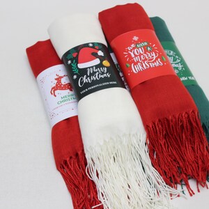 Pode incluir: Tr&ecirc;s cachec&oacute;is com tema natalino com etiquetas festivas. Os cachec&oacute;is s&atilde;o vermelhos, brancos e verdes. As etiquetas t&ecirc;m diferentes sauda&ccedil;&otilde;es de Natal, incluindo "We wish you a merry Christmas" e "Merry Christmas".