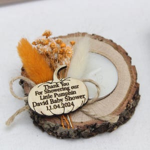K&ouml;nnte beinhalten: Ein rustikaler Holzkerzenhalter mit einem Teelicht, verziert mit Trockenblumen und einem k&uuml;rbisf&ouml;rmigen Holzanh&auml;nger. Auf dem Anh&auml;nger steht "Thank You For Showering our Little Pumphin David Baby Shower 11.04.2024."