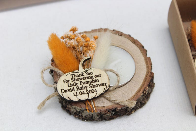 K&ouml;nnte beinhalten: Ein rustikaler Holzkerzenhalter mit einem Teelicht, verziert mit Trockenblumen und einem k&uuml;rbisf&ouml;rmigen Holzanh&auml;nger. Auf dem Anh&auml;nger steht "Thank You For Showering our Little Pumphin David Baby Shower 11.04.2024."
