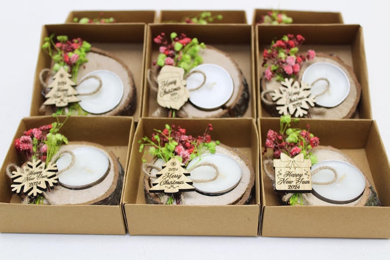 May include: Six small gift boxes containing wooden candle holders decorated with dried flowers and a small wooden ornament. The ornaments have the text "Happy New Year 2023", "2023 Merry Christmas", and "Happy New Year 2023".