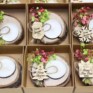 May include: Six small, brown, wooden boxes with lids, each containing a small, white candle in a wooden holder. The boxes are decorated with dried flowers, small wooden ornaments, and the words "Merry Christmas 2024" or "Happy New Year 2024".