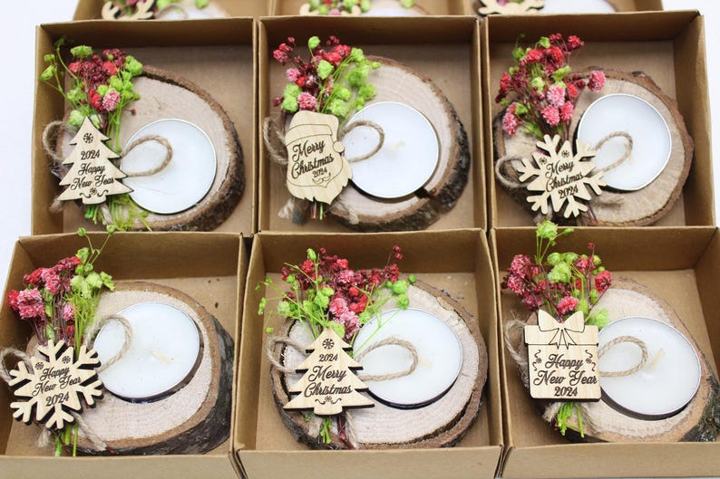 May include: Six small, brown, wooden boxes with lids, each containing a small, white candle in a wooden holder. The boxes are decorated with dried flowers, small wooden ornaments, and the words "Merry Christmas 2024" or "Happy New Year 2024".