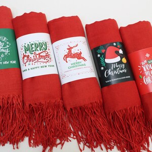 Pode incluir: Cinco cachec&oacute;is vermelhos com franjas e diferentes designs de Natal. Os designs incluem uma rena, um chap&eacute;u de Papai Noel e as palavras "Feliz Natal".