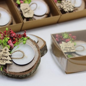May include: A set of small wooden candle holders with a clear glass votive candle, decorated with dried flowers and a wooden ornament that says "2024 Merry Christmas".