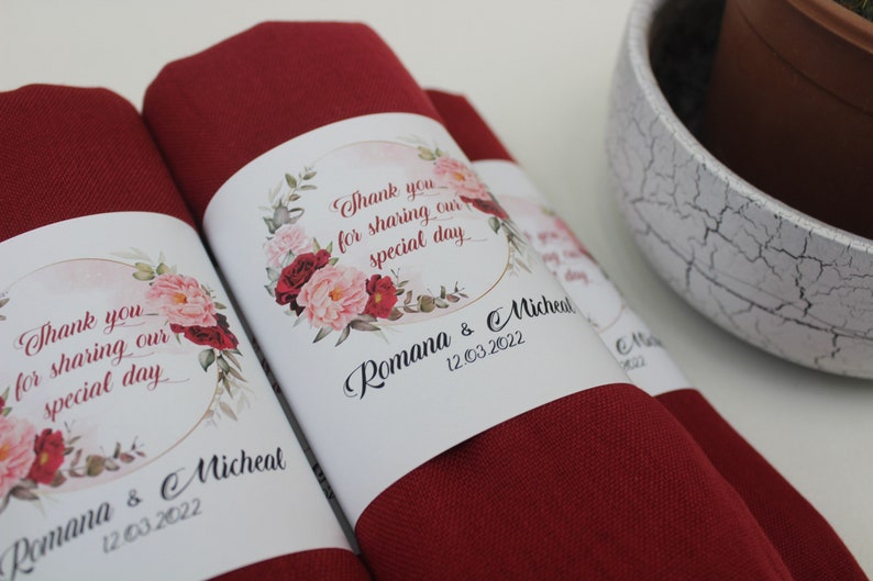 May include: Red fabric wrapped around a white card with a floral design and the text "Thank you for sharing our special day Romana & Micheal 12.03.2022".