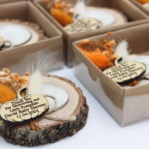 K&ouml;nnte beinhalten: Babyparty-Gastgeschenke aus Holz mit einem k&uuml;rbisf&ouml;rmigen Anh&auml;nger, einer kleinen Kerze und getrockneten Blumen. Jedes Gastgeschenk wird in einer kleinen Box mit transparentem Deckel pr&auml;sentiert. Der Anh&auml;nger tr&auml;gt die Aufschrift "Thank You For Showering our Little Pumpkin David Baby Shower 11.04.2024."
