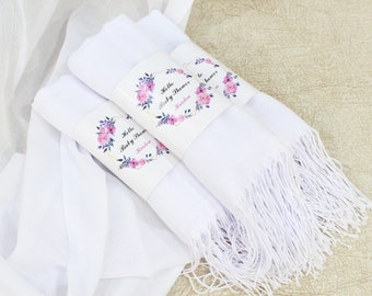 Könnte beinhalten: Drei weiße Schals mit Fransen, jeder mit einem floralen Papierband umwickelt, auf dem "Hello Baby Shower" und ein Name steht.