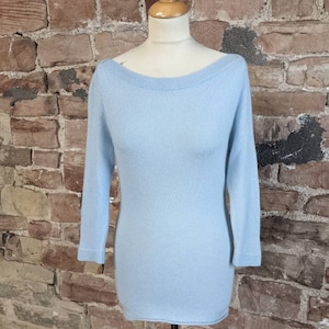 Könnte beinhalten: Ein hellblauer, langärmliger Pullover mit einem Boot Ausschnitt.