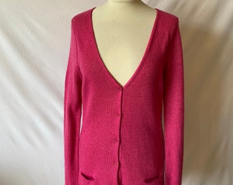May include: A pink knitted cardigan with a v-neck and button closure. The cardigan has two pockets on the front.