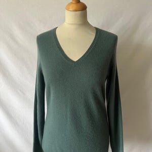 May include: A teal green v-neck sweater with long sleeves.