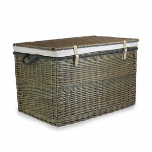 May include: A large, rectangular wicker storage basket with a natural brown finish. The basket has a white canvas lid with leather straps and a rope trim.