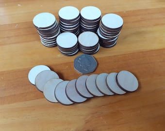 May include: A pile of 25 natural wood circles, each approximately 2 inches in diameter, with a brown edge. A single coin is placed in front of the pile for size comparison.