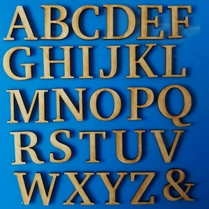 May include: A set of uppercase wooden letters, including the alphabet and an ampersand. The letters are a light brown colour and are arranged in rows on a blue background.