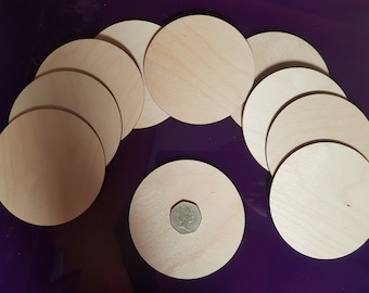 May include: Ten round wooden discs, approximately 3 inches in diameter, arranged in a semi-circle on a purple surface. One disc is in the center of the image with a coin on top.