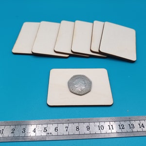 Op de afbeelding: Een set van acht onafgewerkte vierkante houten onderzetters, elk ongeveer 9 cm bij 6 cm. Een Britse munt is op een van de onderzetters geplaatst ter vergelijking van de grootte.