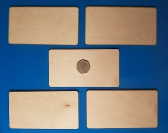 以下が含まれることがあります： 青い背景に、空白の四角い木製の看板が5つあります。1つの看板の上にコインが置かれています。