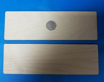 以下が含まれることがあります： 2つの長方形の無垢材、1つは他方よりわずかに大きい。大きい方の木材の上に、スケールを示すためにコインが置かれている。