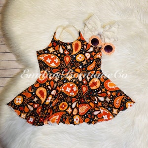 May include: A black and orange paisley print dress with a white lace trim. The dress has a halter neckline and a ruffled skirt.