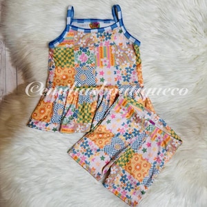 May include: A patchwork print sleeveless dress and matching shorts set for girls. The dress has a ruffled hem and the shorts have a pink waistband. The fabric is a soft, lightweight cotton blend.