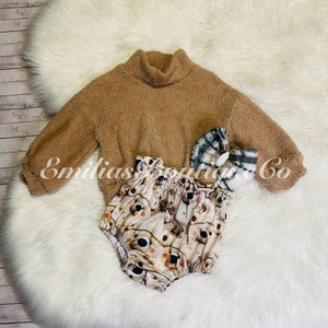 May include: A brown fuzzy sweater with a turtleneck and long sleeves, a white and brown patterned baby onesie, and a plaid headband.