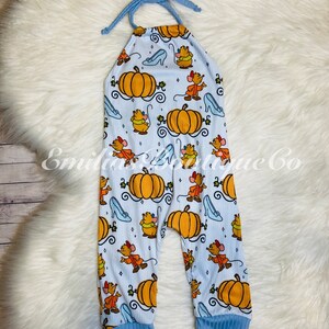 May include: A light blue baby onesie with a pumpkin and Cinderella glass slipper print. The onesie has a halter neck style and blue trim on the straps and legs.