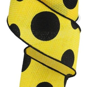 May include: A roll of yellow ribbon with large black polka dots. The ribbon is made of a textured material and is ideal for crafting, gift wrapping, or decorating. The ribbon is approximately 2 inches wide.