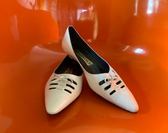 May include: A pair of white leather shoes with cutouts and laces. The shoes have a pointed toe and a low heel. The brand name "Dreaming" is visible on the inside of one shoe.