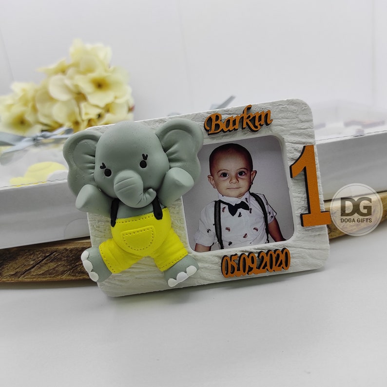 May include: A white wooden photo frame with a gray elephant figurine, a photo of a child, and the text "Barkın 05.09.2020" and "DG Doga Gifts".