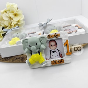 May include: A white photo frame with a gray elephant figurine, a photo of a baby boy, and the text "Barkın 05.09.2020". The frame has a wooden texture and a number "1" in orange.