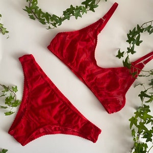 May include: Red lace lingerie set with a floral pattern. The set includes a bra and panty.