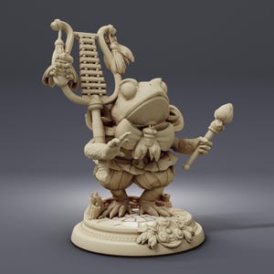 May include: A detailed, beige figurine of a frog dressed in ornate clothing, holding a staff and a musical instrument. The frog has a bow tie with a bee emblem and stands on a decorative base with floral and architectural elements. The figurine is a fantasy-themed collectible.