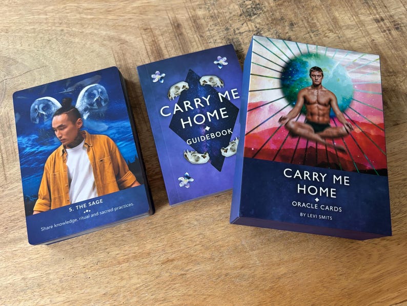 May include: A blue and white oracle card deck with a guidebook. The deck is titled "Carry Me Home Oracle Cards" by Levi Smits. The guidebook is titled "Carry Me Home Guidebook".