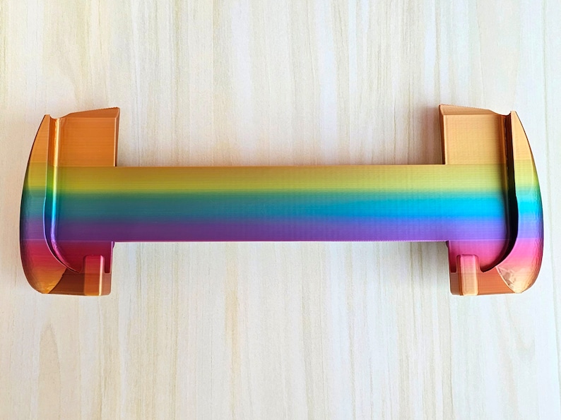 Puede incluir: Un soporte de metal de color arco&iacute;ris con un acabado dorado. El soporte est&aacute; dise&ntilde;ado para sostener un estante u otro objeto.
