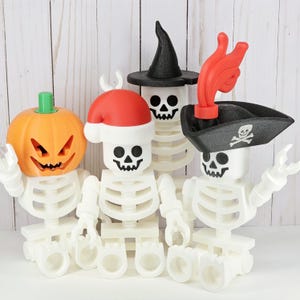 May include: Three white skeleton figures wearing different Halloween hats. One skeleton is wearing a witch's hat, another is wearing a Santa hat, and the third is wearing a pirate hat.