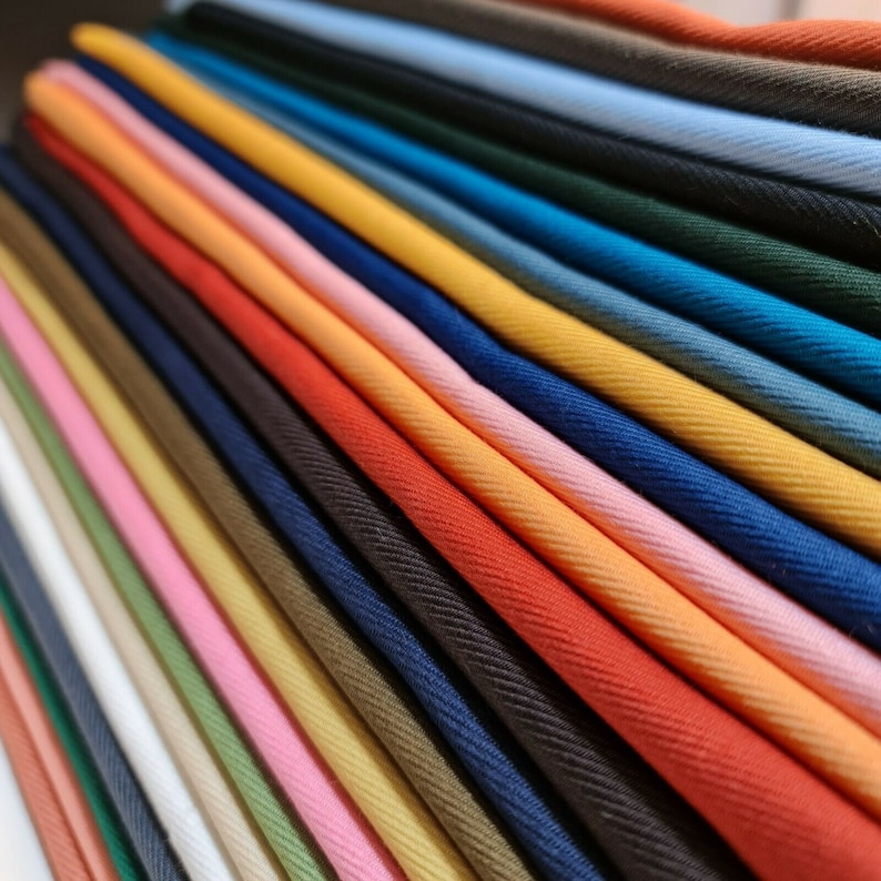 May include: A collection of fabric swatches in various colors, including red, orange, yellow, green, blue, and pink. The fabric is folded and arranged in a fan shape, showcasing the different colors and textures.