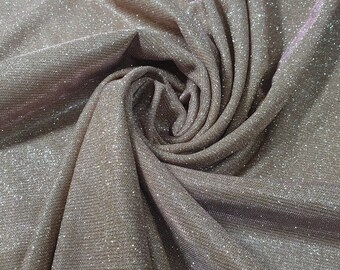 May include: A close-up of a sparkly, light brown fabric with a textured, woven pattern. The fabric is folded and draped, creating a soft, flowing look.