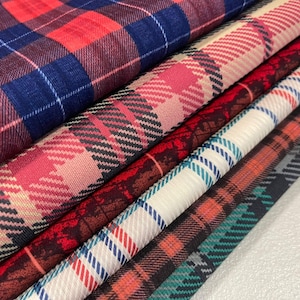 Peut inclure: Gros plan sur plusieurs échantillons de tissu à motifs écossais. Les tissus présentent une variété de couleurs, notamment du rouge, du bleu, du rose, du blanc et du vert. Les motifs sont classiques et conviennent aux projets de vêtements ou de décoration intérieure.