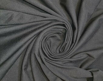 May include: Black fabric with a smooth, soft texture. The fabric is draped and folded, creating a swirling pattern.