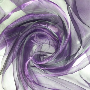 May include: Purple sheer fabric with a shimmery finish, draped and folded to create a swirling pattern.